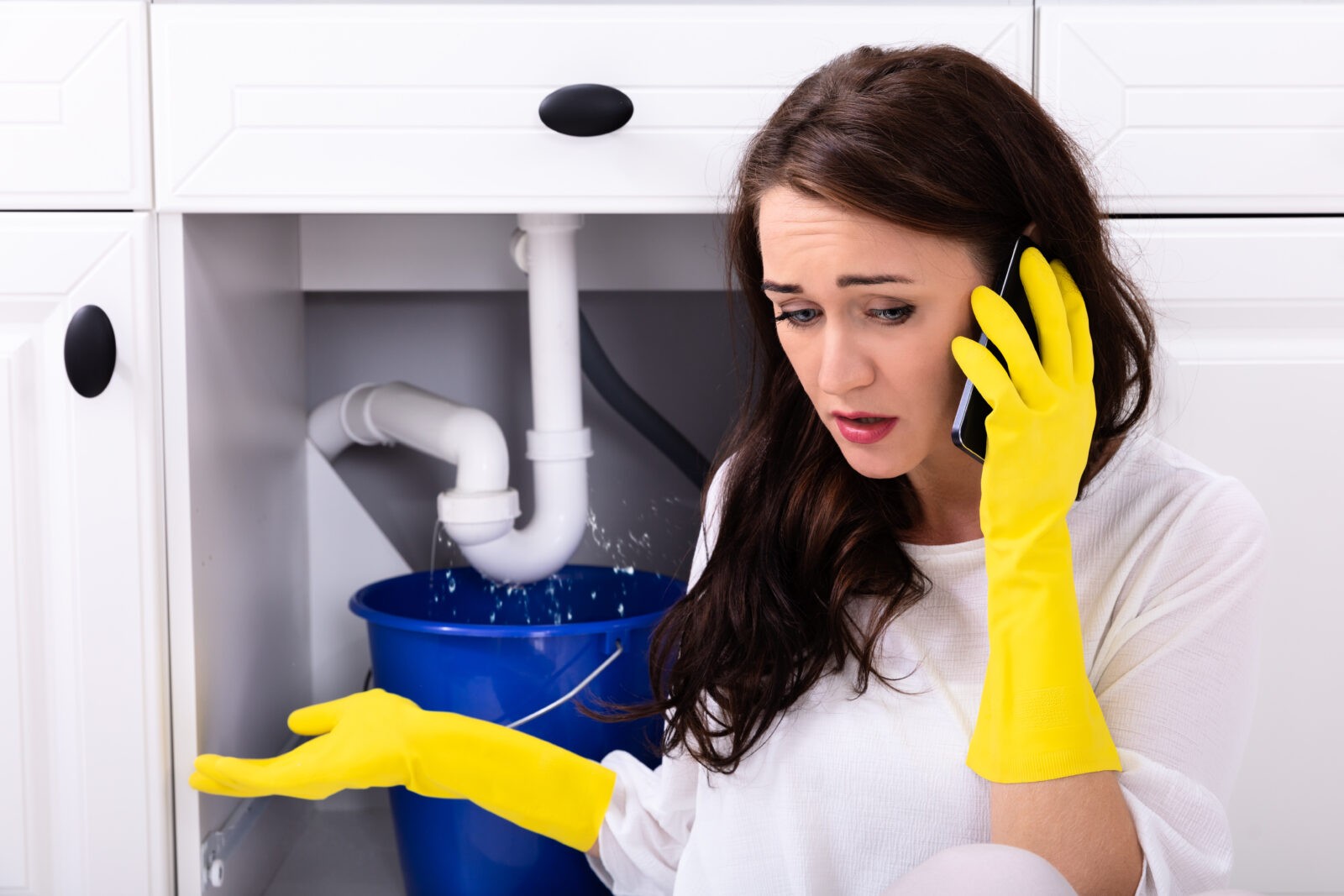 Woman Calling Plumber in Katy, TX due to a plumbing emergency related to a leaky pipe under her sink.